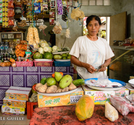 photo of a woman selling various things at the front of her house